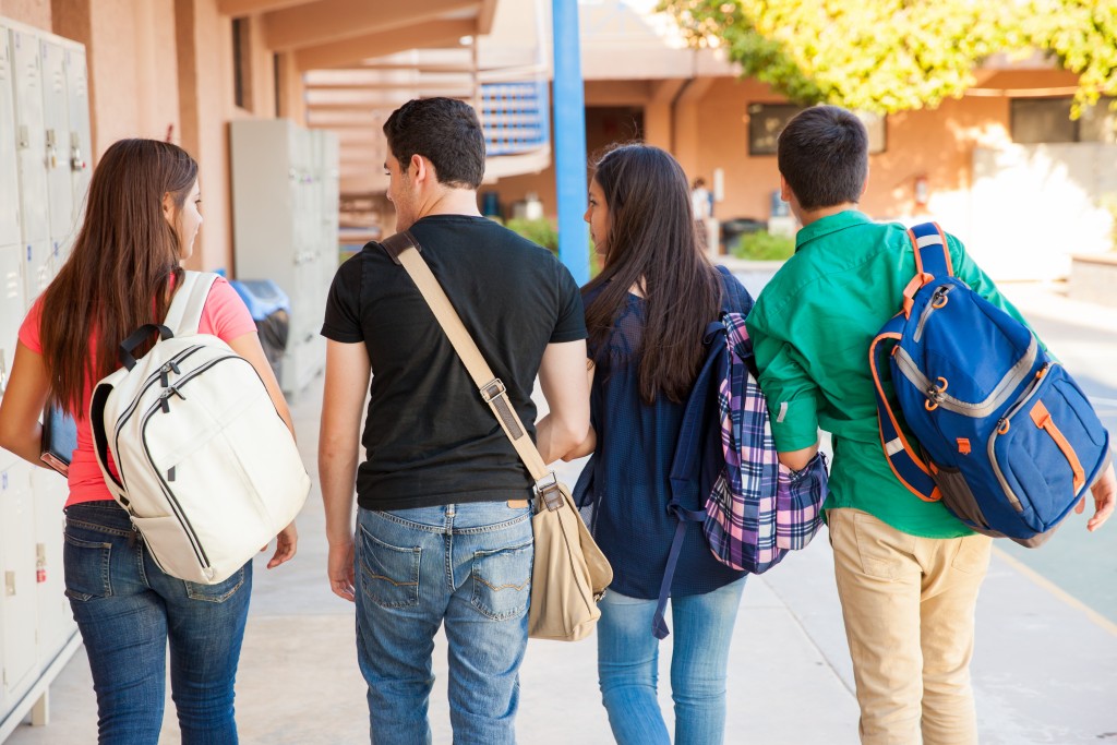 Rear view of a bunch of high school students walking down the hallway