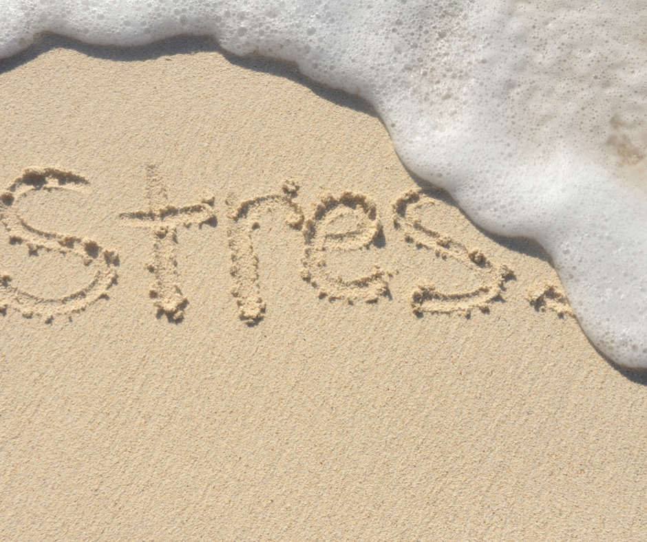 stress written in the sand with a wave crashing over it